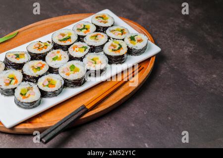 Reis mit Salz und Sesamöl gewürzt und in ein Blatt gerösteten gim (getrockneter Lava) mit Spinat, Karotten und eingelegtem weißem Rettich gerollt. Der lange Stockfoto