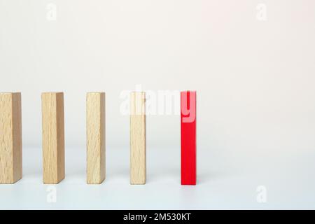 Ein roter Holzblock zwischen dem Holzblock auf weißem Hintergrund. Ein anderes Konzept sein. Stockfoto