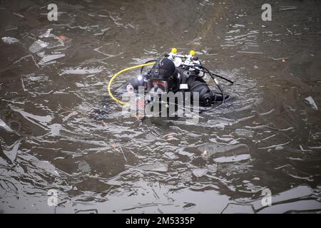 Berlin, Deutschland. 25. Dezember 2022. Ein Polizeitaucher durchsucht den Landwehrkanal. Die Suche nach Beweisen im Fall des spektakulären Juwelendiebstahls aus dem Grünen Gewölbe in Dresden geht an Weihnachten weiter. Nach Angaben der Dresdner Polizei suchen am Sonntag seit den Morgenstunden rund 20 Polizeitaucher aus verschiedenen Staaten im Landwehrkanal am Kiehlufer im Bezirk Neukölln nach Beweisstücken. Kredit: Christophe Gateau/dpa/Alamy Live News Stockfoto