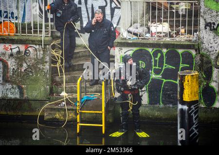 Berlin, Deutschland. 25. Dezember 2022. Einsatzkräfte beobachten eine Durchsuchung im Landwehrkanal. Die Suche nach Beweisen im Fall des spektakulären Juwelendiebstahls aus dem Grünen Gewölbe in Dresden geht an Weihnachten weiter. Nach Angaben der Dresdner Polizei suchen seit den Morgenstunden am Sonntag rund 20 Polizeitaucher aus verschiedenen Bundesländern im Landwehrkanal am Kiehlufer im Bezirk Neukölln nach Beweisstücken. Kredit: Christophe Gateau/dpa/Alamy Live News Stockfoto