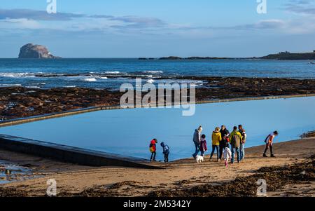 North Berwick, East Lothian, Schottland, Vereinigtes Königreich, 24. Dezember 2022. UK Weather: Eine Gruppe von Menschen, die morgens am milden sonnigen, ruhigen Heiligabend am Strand von Milsey Bay an der Küste von Firth of Forth mit dem Bass Rock in der Ferne genießen. Kredit: Sally Anderson/Alamy Live News Stockfoto