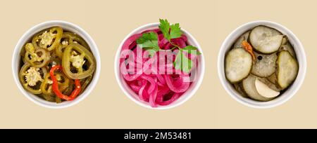 Muster aus eingelegtem Jalapeno-Paprika, roten Zwiebeln und Gurken in weißen Schüsseln auf gelbem Hintergrund. Traditionelle Fleischsnacks. Gesunde fermentierte Nahrung. Stockfoto