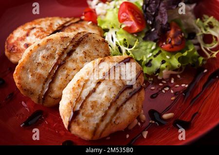 Dampfgaren Sie Koteletts mit Hähnchen auf einem Teller mit Gemüse und Salat Stockfoto