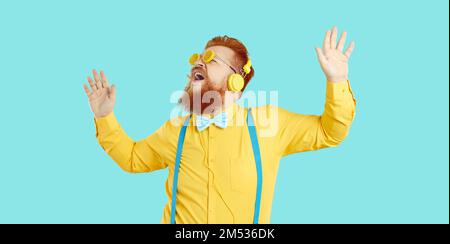 Lustiger, fröhlicher, bärtiger Mann in orangefarbener Sonnenbrille, der Musik hört und tanzt Stockfoto