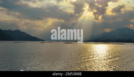 Sonnenuntergang in der Bucht von Hiroshima, Seto-Binnensee, zwischen der Insel Itsukushima und der Stadt Hatsukaichi. Präfektur Hiroshima, Japan. Stockfoto