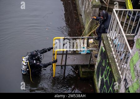 Berlin, Deutschland. 25. Dezember 2022. Ein Polizist klettert nach der Suche aus dem Landwehrkanal. Die Suche nach Beweisen im Fall des spektakulären Juwelendiebstahls aus dem Grünen Gewölbe in Dresden geht an Weihnachten weiter. Nach Angaben der Dresdner Polizei suchen am Sonntag seit den Morgenstunden rund 20 Polizeitaucher aus verschiedenen Staaten im Landwehrkanal am Kiehlufer im Bezirk Neukölln nach Beweisstücken. Kredit: Christophe Gateau/dpa/Alamy Live News Stockfoto