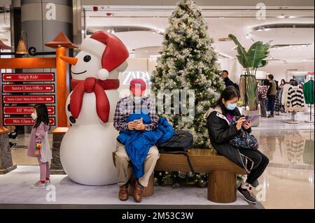 Hongkong, China. 16. Dezember 2022. Shopper sitzen auf einer Bank neben einem Weihnachtsbaum und einer Schneemanninstallation in einem Einkaufszentrum in Hongkong. (Foto: Miguel Candela/SOPA Images/Sipa USA) Guthaben: SIPA USA/Alamy Live News Stockfoto