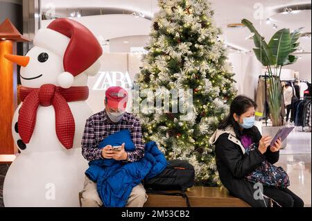 Hongkong, China. 16. Dezember 2022. Shopper sitzen auf einer Bank neben einem Weihnachtsbaum und einer Schneemanninstallation in einem Einkaufszentrum in Hongkong. (Kreditbild: © Miguel Candela/SOPA Bilder über ZUMA Press Wire) Stockfoto
