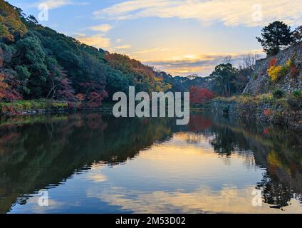Sonnenaufgang über einem ruhigen Teich mit wunderschönen Herbstfarben im Schlosspark Stockfoto