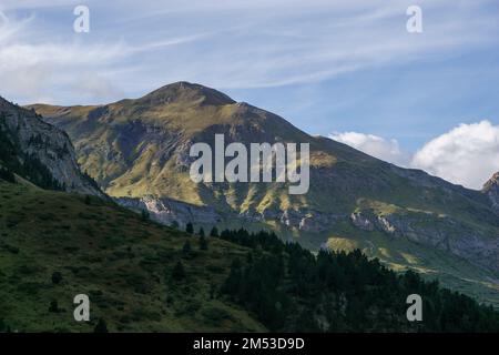 Goldenes Sonnenlicht fällt am Herbstabend auf einem grünen, grasbedeckten Hügel in der Berglandschaft nahe Gavarnie in Pyrenäen, Nouvelle-Aquitaine, Frankreich Stockfoto