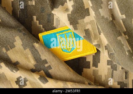 Pixeliges digitales Tarnmaterial mit ukrainischer Flagge und Wappen auf Chevron in Blau und Gelb. Attribute der ukrainischen Soldatenuniform Stockfoto