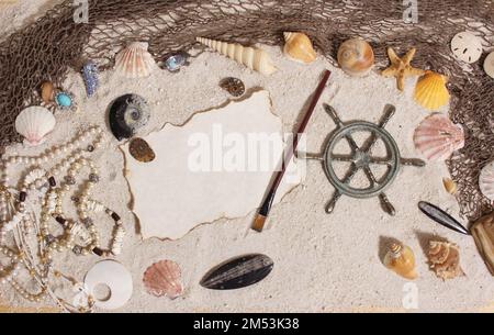 Ein Blick von oben auf das Captains Wheel mit Fischnetz und Meeresmuscheln auf Sand Stockfoto