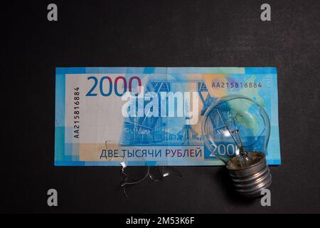 Kaputte Glühbirne mit Glasscherben auf russischem Rubel. Konzept der Strompreise und die Stromversorgungskrise in Russland Stockfoto
