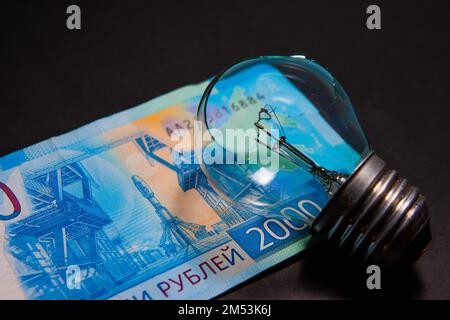 Kaputte Glühbirne mit Glasscherben auf russischem Rubel. Konzept der Strompreise und die Stromversorgungskrise in Russland Stockfoto