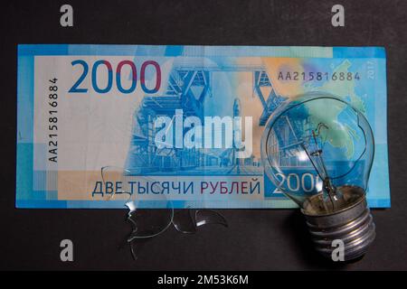 Kaputte Glühbirne mit Glasscherben auf russischem Rubel. Konzept der Strompreise und die Stromversorgungskrise in Russland Stockfoto