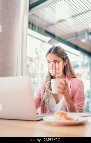 Eine friedlich lächelnde Geschäftsfrau der Millennials, die ein Notebook benutzt und an einem modernen Arbeitsplatz ein Videogespräch führt Stockfoto