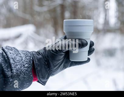 Handschuh zum Mitnehmen, Kaffeetasse aus umweltfreundlichem Silikon, Tasse zum Mitnehmen im Winter, bei Schnee. Hochwertiges Foto Stockfoto