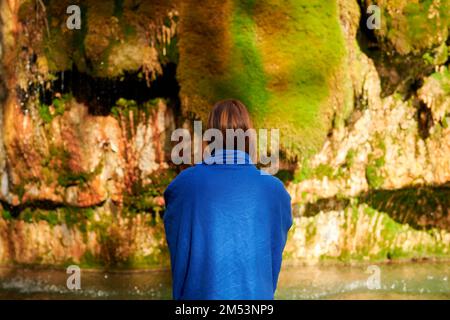 Eine Nahaufnahme einer Frau, die gegen den Wasserfall steht Stockfoto