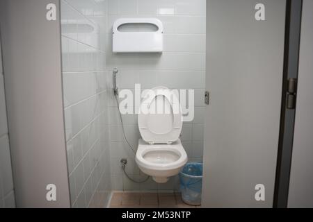 Schule, Universität oder öffentliche Toilette, weiße Toilette mit Waschwerkzeug oder 'Shattaf' und Mülleimer. Arabische Toilette mit Waschspray, moderne Toilette. Stockfoto