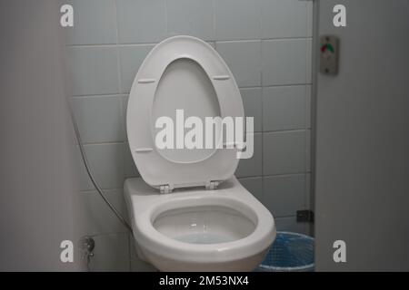 Schule, Universität oder öffentliche Toilette, weiße Toilette mit Waschwerkzeug oder 'Shattaf' und Mülleimer. Arabische Toilette mit Waschspray, moderne Toilette. Stockfoto