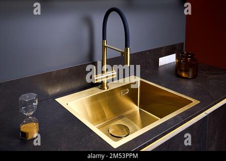 Luxuriöses quadratisches Innenwaschbecken aus goldenem Messing und Wasserhahn-Doppelhahn-Mixer in zeitgemäßem, modernem Design mit Steinmarmor-Steingut-Arbeitsplatte in Schwarz und Stockfoto