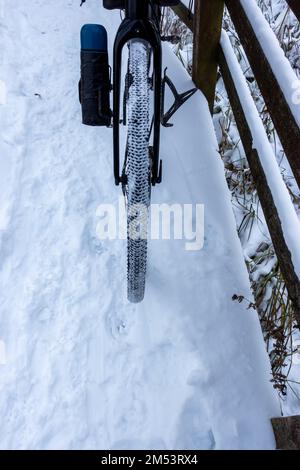 Ein schneebedeckter Fahrradreifen während einer Winterfahrt auf schneebedeckten Pfaden Stockfoto
