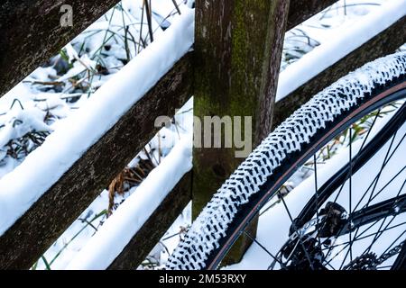 Ein schneebedeckter Fahrradreifen während einer Winterfahrt auf schneebedeckten Pfaden Stockfoto