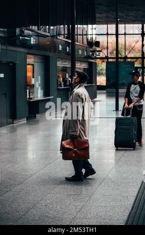 Ein vertikales Bild eines Mannes auf einem Bahnhof, der auf seine Abfahrt in Lodz, Polen wartet Stockfoto