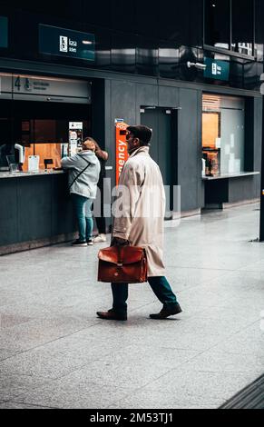 Ein vertikales Bild eines Mannes auf einem Bahnhof, der auf seine Abfahrt in Lodz, Polen wartet Stockfoto