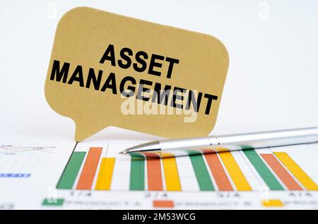 Geschäftskonzept. Auf den Finanzplänen liegen ein Stift und ein Schild mit der Aufschrift Asset Management Stockfoto