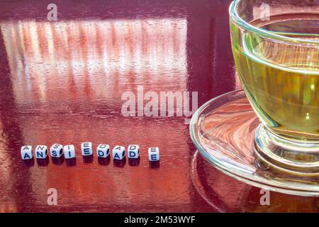 Goiania, Goiás, Brasilien – 25. Dezember 2022: Detail einer Tasse Tee auf dem glänzenden Tisch mit dem Wort "Angst" in Stücken. Stockfoto