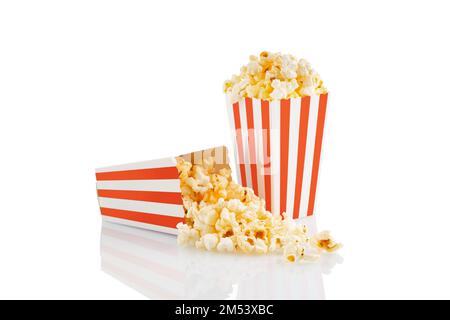 Zwei rot-weiß gestreifte Eimer mit leckerem Käsepopcorn, isoliert auf weißem Hintergrund. Schachtel mit Streuung von Popcornkörnern. Filme, Kino und Stockfoto