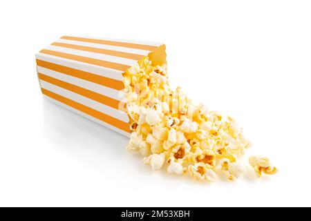 Leckeres Käsepopcorn, das aus einem gelb gestreiften Eimer fällt, isoliert auf weißem Hintergrund. Streuung von Popcornkörnern. Filme, Kino und en Stockfoto