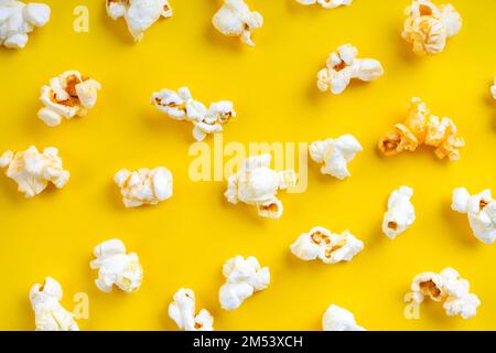 Verstreutes, leckeres Käsepopcorn, isoliert auf gelbem Hintergrund. Draufsicht, flach liegend, Banner, Tapete Stockfoto