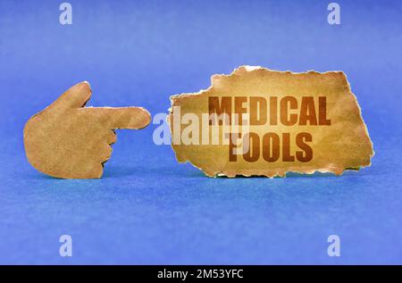 Medizinisches Konzept. Auf einer blauen Oberfläche zeigt eine Kartonhand auf ein Schild mit der Aufschrift - Medical Tools Stockfoto