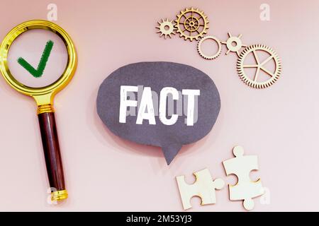 Fakt - Wort durch Vergrößerungsglas auf gelbem Tisch. Stockfoto
