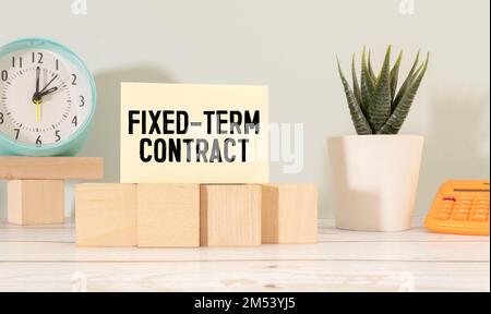 Uhr mit Blick von oben und Miniaturleute mit Text Festzeitvertrag auf weißem Puzzlehintergrund. Stockfoto