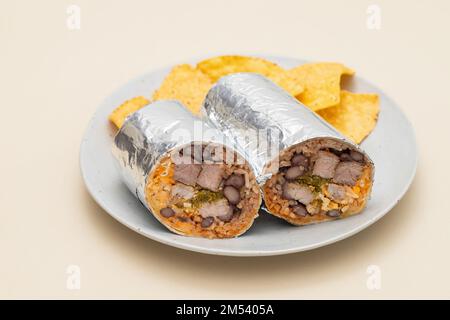 Mexikanischer Rindfleischburrito auf einem kleinen Teller mit Chips Nachos auf dem Teller Stockfoto