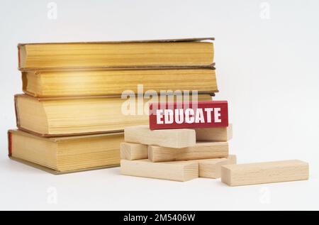 Bildungskonzept. Auf einer weißen Oberfläche, einem Stapel von Büchern und Holzblöcken, auf einem roten Block ist eine Inschrift - pädagogisch Stockfoto