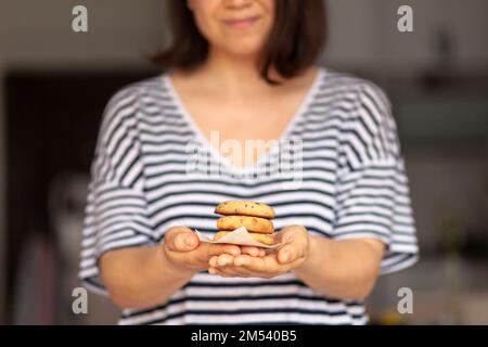 Eine junge Frau hält einen frisch gebackenen Keks Stockfoto