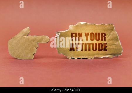 Geschäfts- und Technologiekonzept. Auf einer braunen Oberfläche zeigt eine Papphand auf ein Schild mit der Aufschrift „Beheben Sie Ihre Einstellung.“ Stockfoto