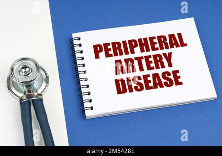 Medizinisches Konzept. Auf einer blau-weißen Oberfläche liegt ein Stethoskop und ein Notizblock mit der Aufschrift - periphere Arterienerkrankung Stockfoto