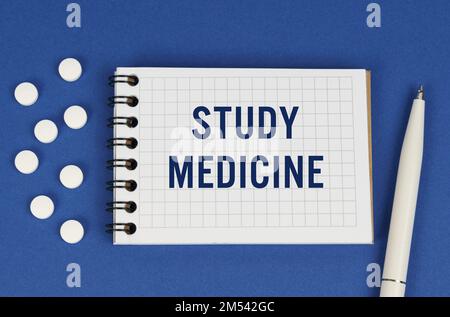 Medizinisches Konzept. Auf blauem Hintergrund, einem Stift, Tabletten und einem Notizblock mit der Beschriftung - STUDIENMEDIKAMENT Stockfoto