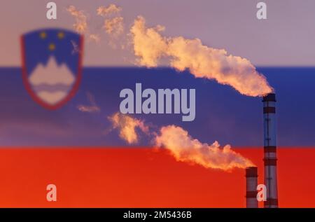 Ökologisches Konzept. Vor dem Hintergrund der slowenischen Flagge strömt Rauch aus den Schornsteinen eines Industrieunternehmens und verschmutzt die Luft. Stockfoto