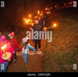 Serina Italien Dezember 24 2022: Menschen mit Fackeln gehen auf die Hütte zu, um den weihnachtstag zu feiern Stockfoto