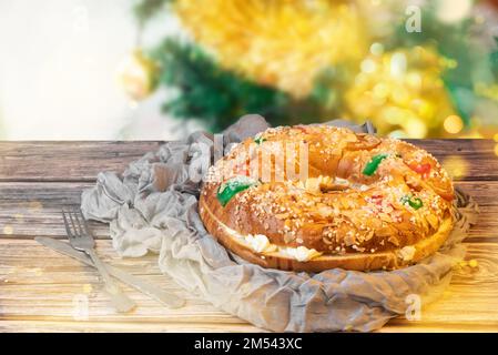 Epiphany Kuchen gefüllt mit Sahne 'Roscon de Reyes' neben einem Weihnachtsbaum. Typisch spanisches Süßes gegessen am Tag der drei Könige Stockfoto