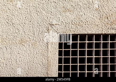 Metallgitter in der Steinwand. Gefängnisfenster mit Gitterrosten Stockfoto