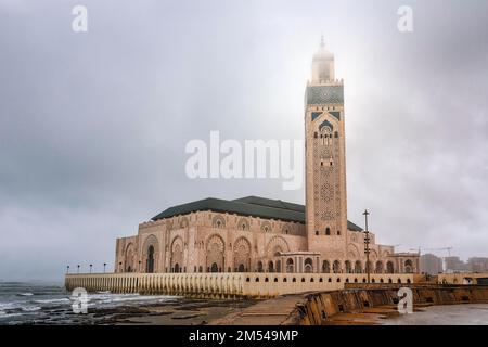 Hassan II Moschee an der felsigen Küste, maurische Architektur, bewölkt, Minarett im Nebel, düstere Atmosphäre, Casablanca, Marokko Stockfoto