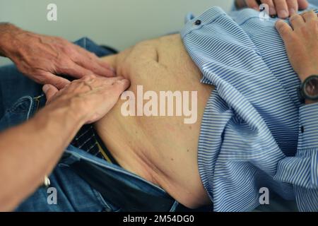 Dieser Internist im Zentrum einer größeren Stadt arbeitet hauptsächlich als Hausarzt. Das Foto zeigt: Untersuchung des Abdomens, Deutschland Stockfoto