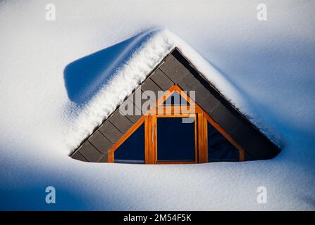 Holzfenster auf dem Dach mit Schnee bedeckt, Österreich Stockfoto